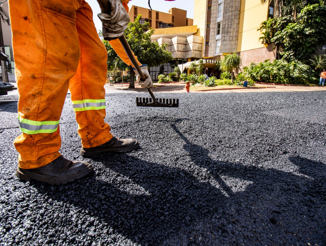 services-01 Worker in orange gear paving a road in Londrina city during daytime.