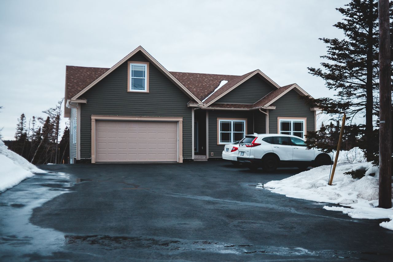 services-01 Exterior of small residential house in neighbourhood with cars parking on snowy ground in misty day