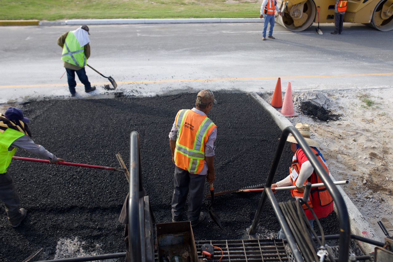 services-04 Group of road construction workers laying fresh asphalt outdoors during the day.